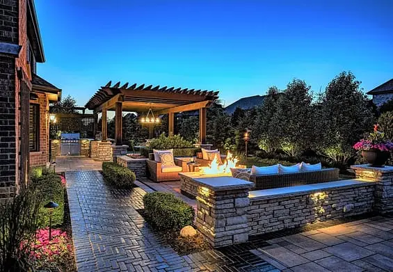 A brick patio with a pergola, fireplace, and seating area.